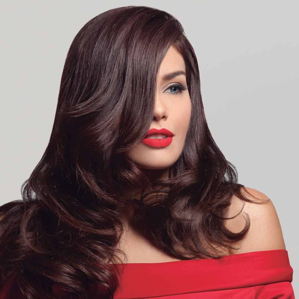 A beautiful Latina model with long flowing brunet hair. She's wearing a red red dress with red lipstick that makes her radiate beauty and fashion. Styled with Firenze Professional hair products.