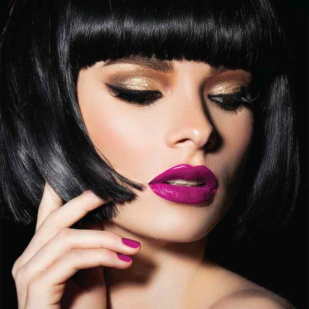 Short bob hair style, colored a dark shiny black on a Latina model with magenta lipstick looking downards over her shoulder with beauty. Hair color created by abril et NatureColor.